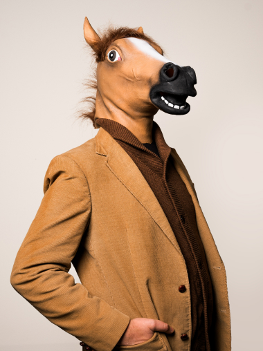 A person wearing a sportcoat and a horse mask